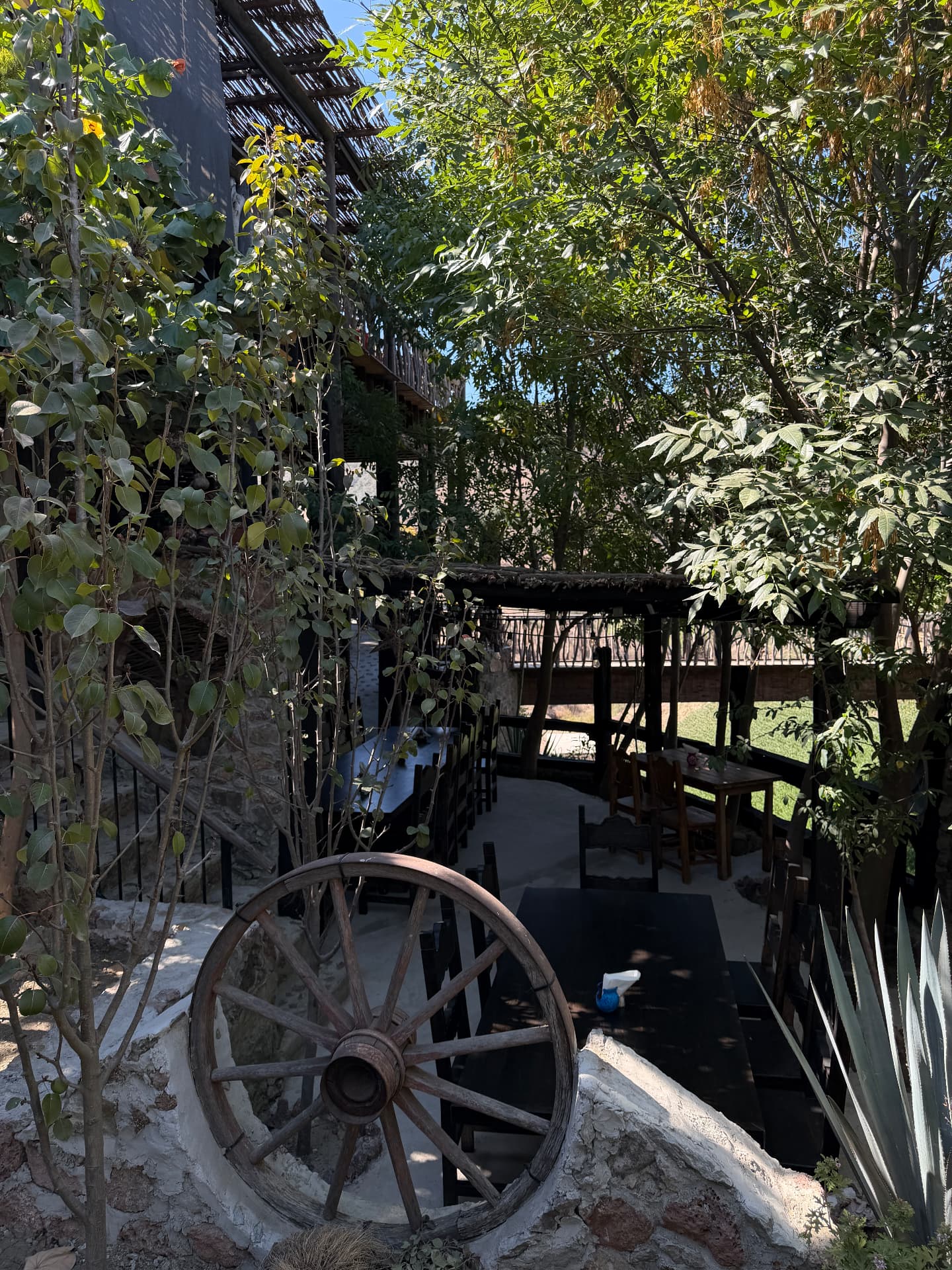 Jardín con mesas y rueda de carreta en Rancho 21